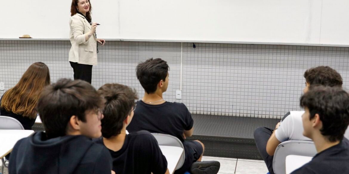 Professora orienta alunos em sala de aula sobre redação.