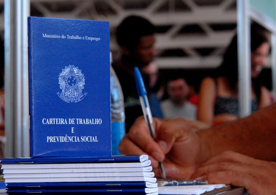 Carteiras de trabalho azuis sobre balcão de atendimento.