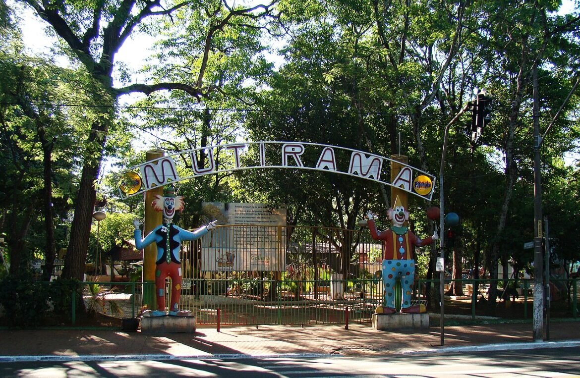 Portão de entrada do Parque Mutirama entre árvores, com esculturas de palhaços.