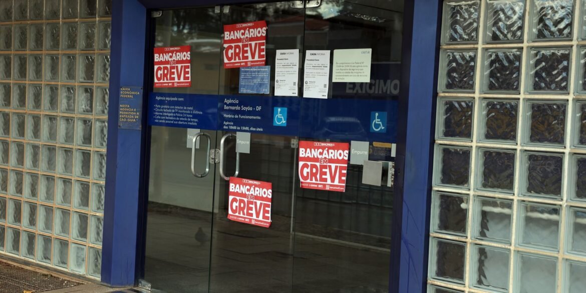 Porta de agência da Caixa com cartazes de bancários em greve.